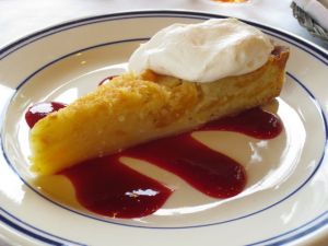 A peach tart with raspberry sauce and a dollop of whipped cream